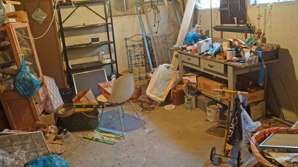 Cluttered basement filled with junk and household items, showing the need for professional hoarding cleanup.